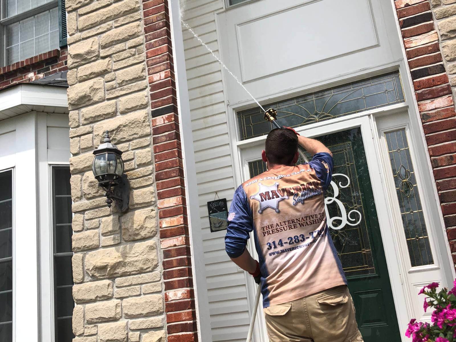 Maverick Softwash technician soft washing a brick and siding front entry in St. Louis